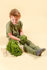 Little boy making a funny face refusing to eat his broccoli. Fresh vegetables.Healthy food for...