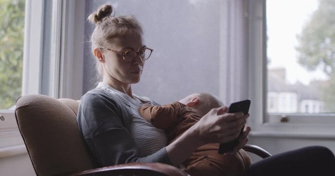 Single Mother comforting baby and look at smart phone