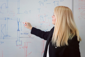 Female Architecture teacher at work. Female professor explain architectural projects to students. Beautiful female university architecture professor explain lessons to multiethnic students.