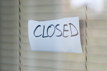 Window and blinds on which a piece of paper with the inscription closed hangs