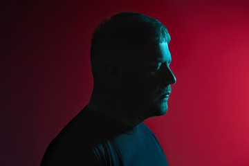 Portrait of a handsome bearded young man in a black sweater posing against a colorful background.