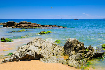 Fototapeta na wymiar Rocks on the beach near the city beach in Lloret de Mar, Costa Brava. The concept of rest.