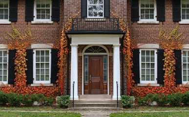 Fototapeta na wymiar Traditional two story brick house with colorful ivy in fall.