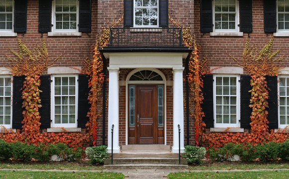 Traditional two story brick house with colorful ivy in fall.
