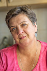 Mature woman in red sitting by the window, smiling