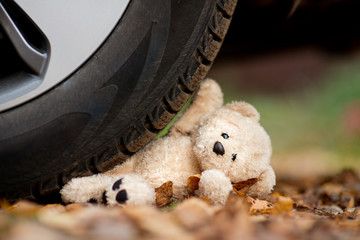 A teddy bear under the wheel of a car