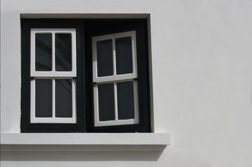 Fototapeta premium A half-open wooden and glass window in a white exterior wall