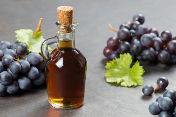 Glass bottle of organic black grape balsamic vinegar made from fermented fresh grapes. Healthy organic food black fruit, selective focus
