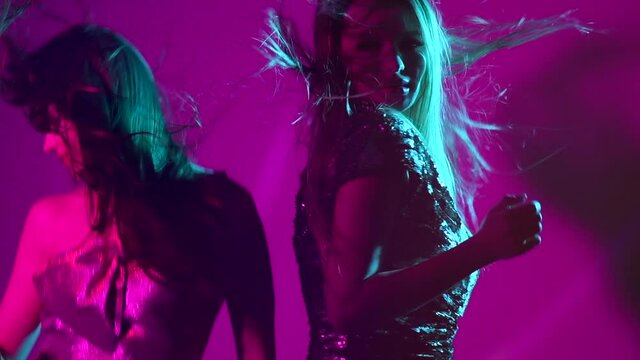 Hot model girls dancing in UV neon lights. Disco party. Sexy young women with perfect slim bodies dancing. Night life. Slow Motion 4K UHD video footage. 3840X2160