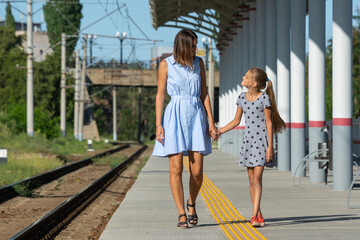 Young beautiful girl and teenage daughter walk on the empty platform of the train station