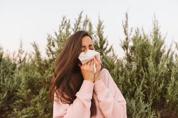 Young woman sneezes with allergies