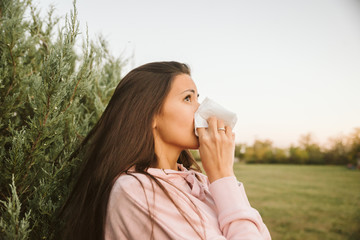 Young woman sneezes with allergies