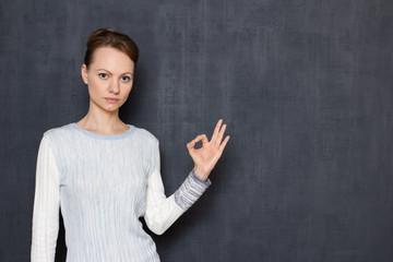 Portrait of serious focused woman showing okay or zero gesture