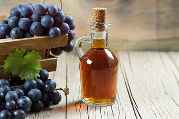 Glass bottle of organic black grape balsamic vinegar made from fermented fresh grapes. Healthy organic food black fruit, selective focus