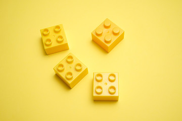 A yellow children's plastic bricks or blocks toy on yellow background