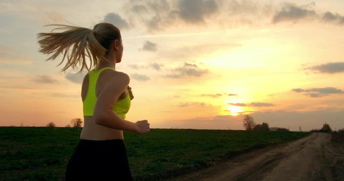 Young girl is running off road at sunset in autumn weather 4K 