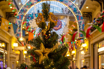 The Christmas tree is decorated with lights, toys, stars, angels, ribbons, cones. Bright, beautiful, festive interior in the background. Bokeh