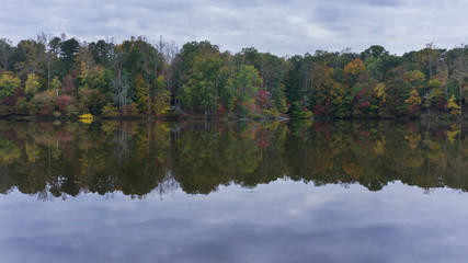Fototapeta premium A scenic autumn view of colorful forest foliage reflecting on a lake.