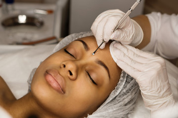 Procedure mechanical face cleaning in beauty salon. Afro american young model getting cosmetic face...