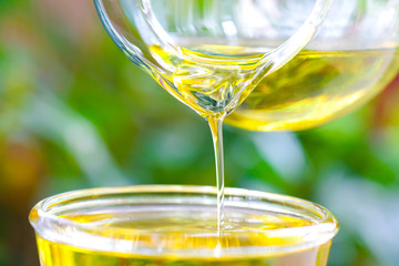 Pouring olive oil in the a glass bowl at stone kitchen and inside green garden view. Prepare for cooking concept. Healthcare and Beauty Concept.