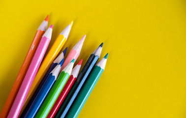 Colorful drawing pencils on yellow background