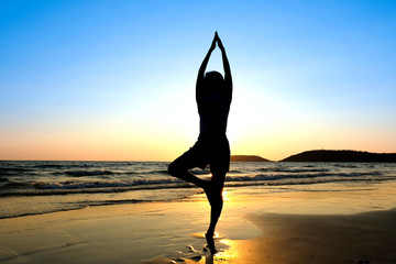 Fototapeta na wymiar Women practice yoga on the beach of the sea during the morning hours.