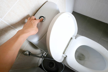 hands of men, press the water button, flush the toilet, the health concept.