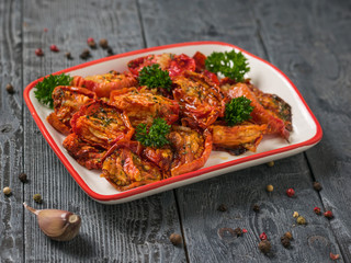 Dried tomatoes with olive oil and garlic on a wooden table. Vegetarian food.