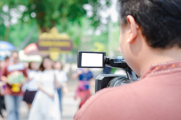 Professional video man hand holding Video camera operator camcorder working with his equipment outdoor with blurred background,copyspace
