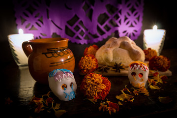 Bread of dead, sugar skulls, coffee and candles on an altar for day of dead.