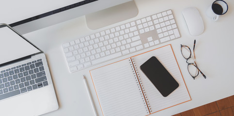 Cropped shot of modern workplace with open blank notebook, smartphone, keyboard computer and desktop computer © bongkarn