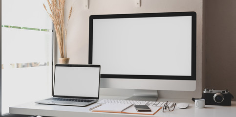 Blank screen desktop computer and laptop in modern workspace