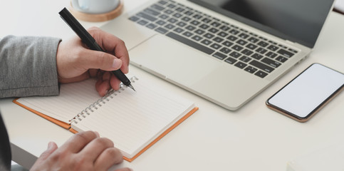 Cropped shot of businessman working his project while writing ideas on notebook