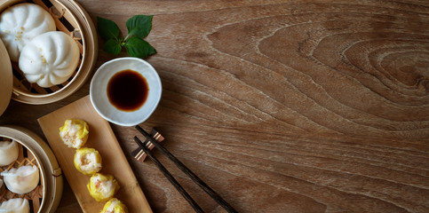 Overhead shot of Chinese steamed dumpling and steamed pork bun in a bamboo steamer with chopstick