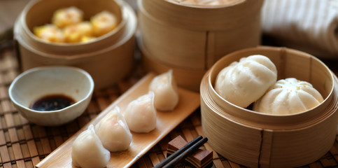 Chinese steamed dumpling and steamed pork bun in a bamboo steamer with chopstick