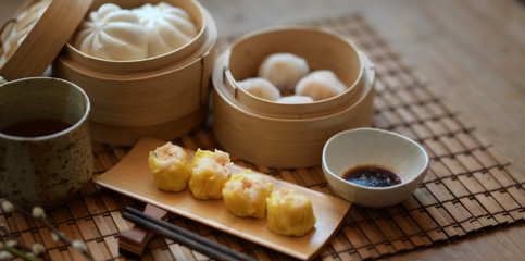 Chinese steamed dumpling and steamed pork bun in a bamboo steamer with chopstick