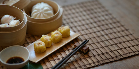 Chinese steamed dumpling and steamed pork bun in a bamboo steamer with chopstick