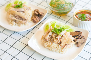 Hainanese Chicken Rice in white plate on the table with soup and spicy dipping sauce ,Thai gourmet steamed chicken with rice