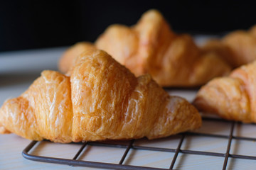 Close up Tasty fresh croissants on cooling rack on wooden table in the morning.