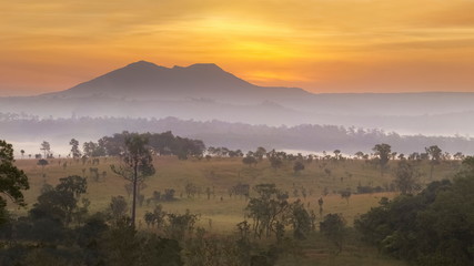 Mountain view panorama misty morning of peak mountain around with green forest and soft fog with yellow sun light in the sky background, sunrise at Thung Salang Luang, Khao Kho, Phetchabun, Thailand.