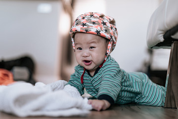 Cute asian little son wearing baby helmet doing tummy time