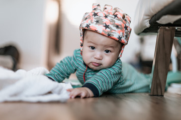 Cute asian little son wearing baby helmet doing tummy time