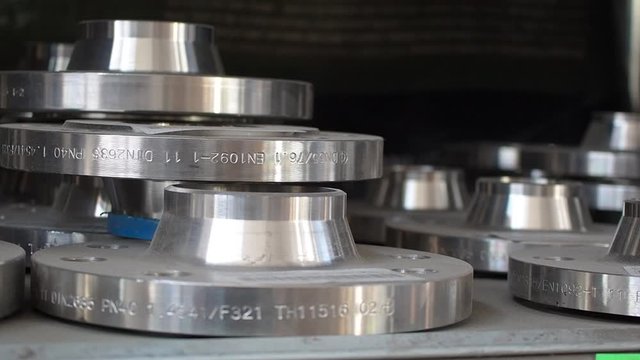 Flanges stacked in warehouse. Stainless steel industrial machine parts.