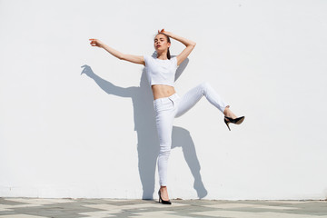 Fototapeta na wymiar Model tests. Young beautiful brunette model posing against a white wall