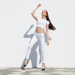 Naklejka premium Model tests. Young beautiful brunette model posing against a white wall