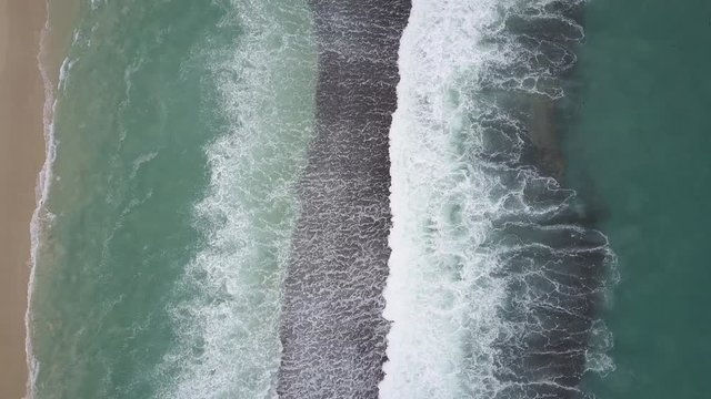 Scenic vertical aerial view of flight above coast, with powerful turquoise ocean waves, white swell as background, backdrop and copy space.