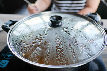 Close up view of hot pot and cover with hot water steam . Shabu Shabu is style beef in hot pot dish of thinly sliced meat and vegetables boiled in water. delicious food most popular in Thailand.