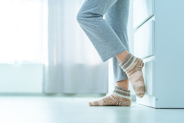 Female legs in cozy soft warm knitted winter socks at home