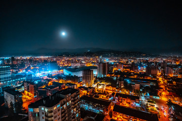 Fototapeta na wymiar Panorama of a luminous night city illuminated by a bright moon