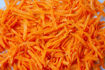 Juicy bright carrots grated on a grater isolated on a white background.